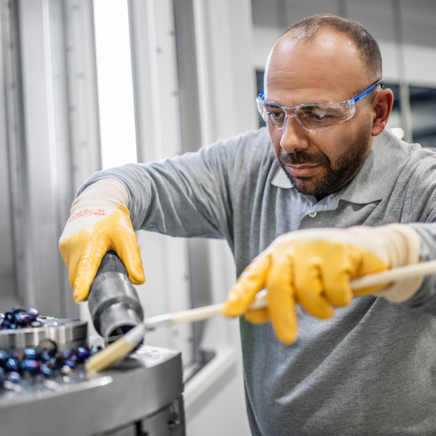 Männliche Reinigungskraft mit Schutzbrille und Handschuhen bei der Reinigung einer Maschine