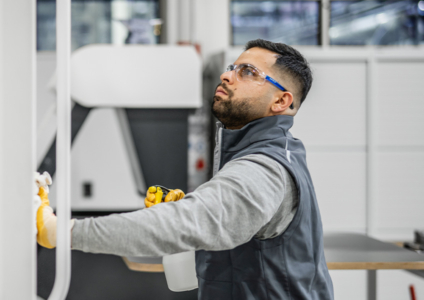 Männliche Reinigungskraft mit Schutzbrille bei der Reinigung einer Maschine