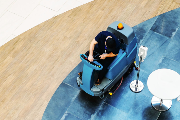 Reinigungskraft auf großen, fahrbaren Bodenreiniger von oben