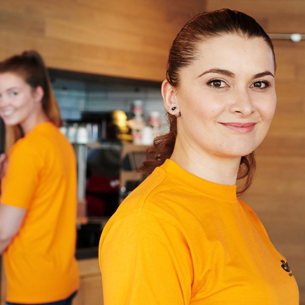 Lächelnde junge Reinigungskraft in orangenem T-Shirt